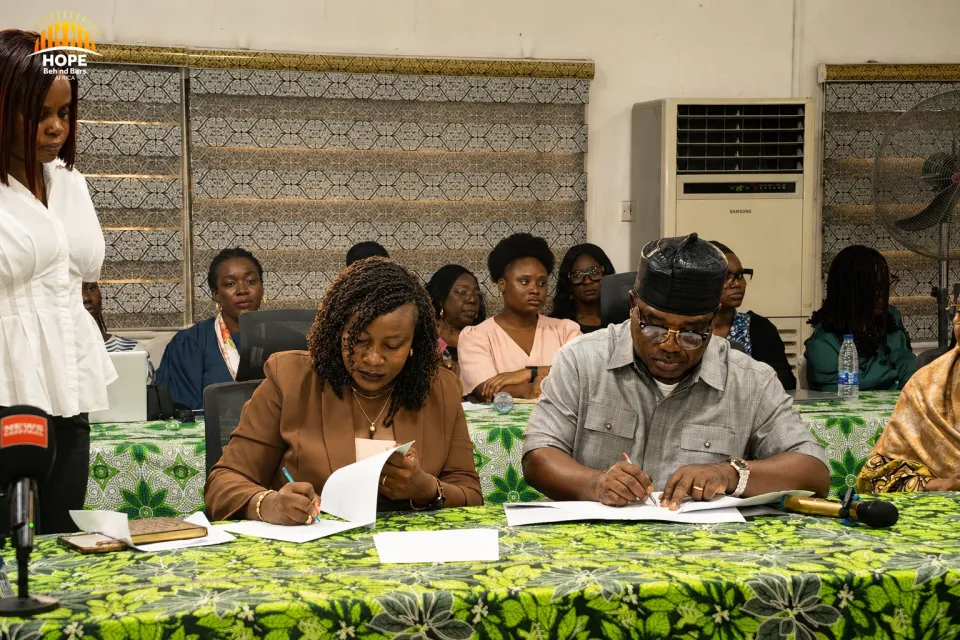 Two signatories sign documents at a table during a signing ceremony.